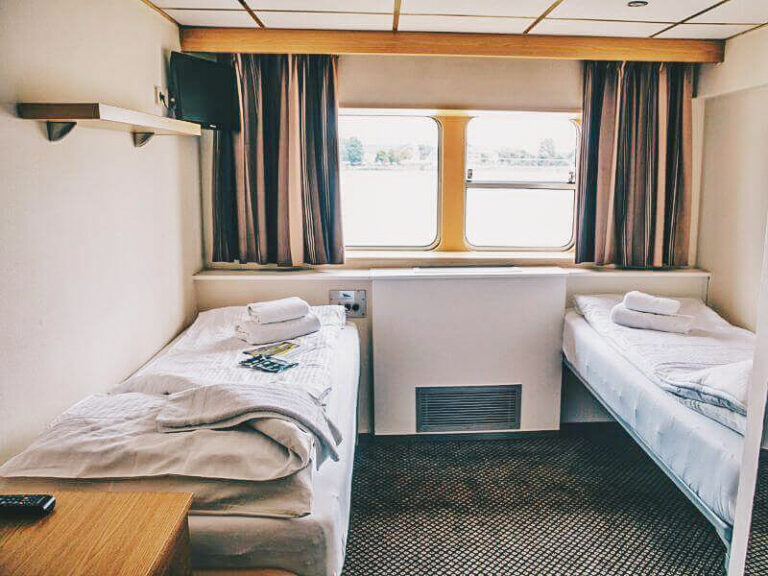 Cabina con due letti singoli e finestra con vista sul fiume.